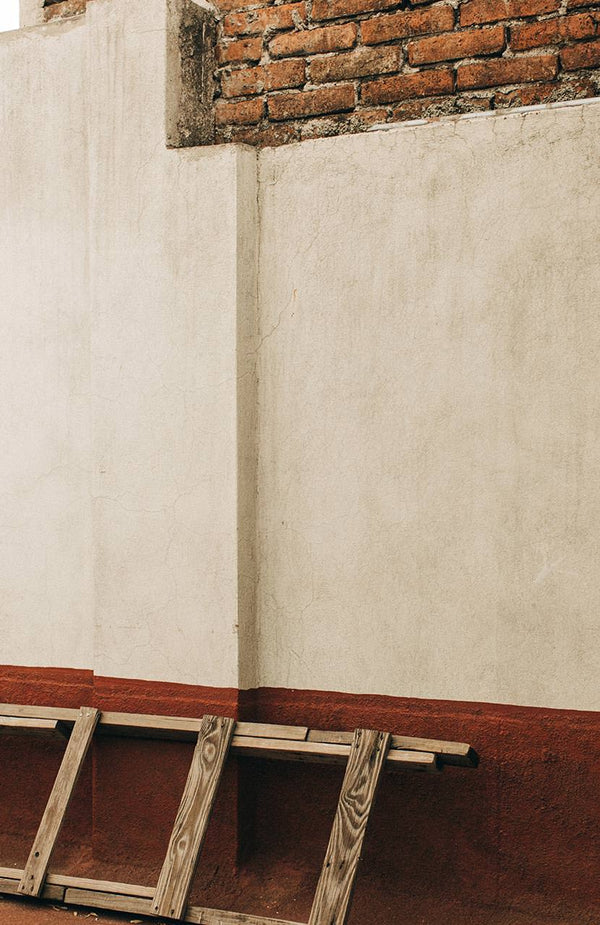 shot of a white and red wall with a ladder on the ground