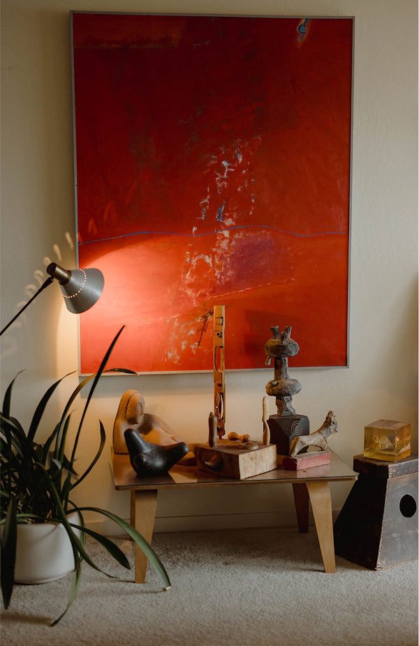 A coffee table in front of a red painting