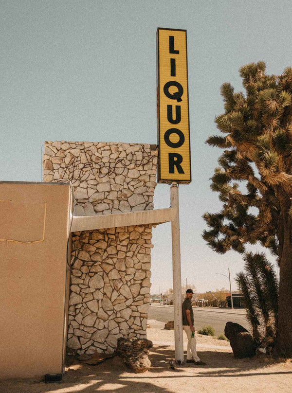 Model standing beneath a vintage liquor store sign