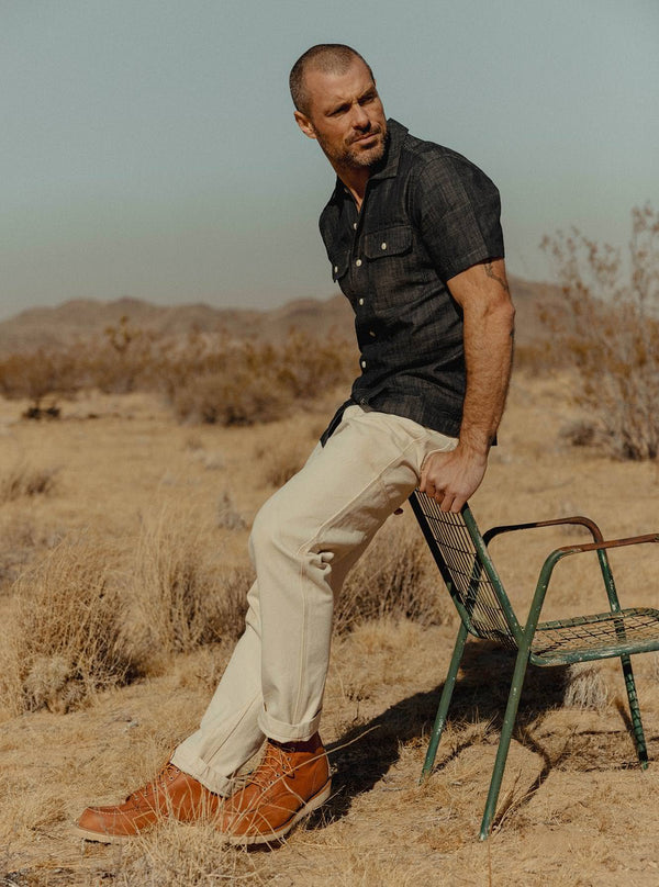Model leaning against a metal chair in the desert