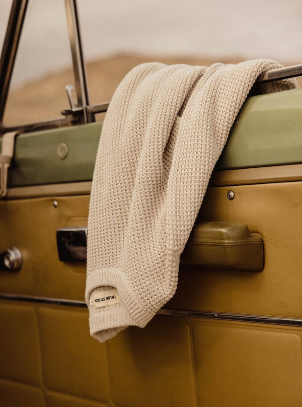 The Ranger Sweater in Heather Fog Linen Waffle hanging on a car door