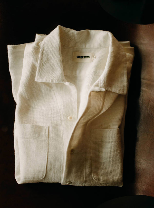 The Conrad Shirt in Vintage White Linen, folded on a leather chair