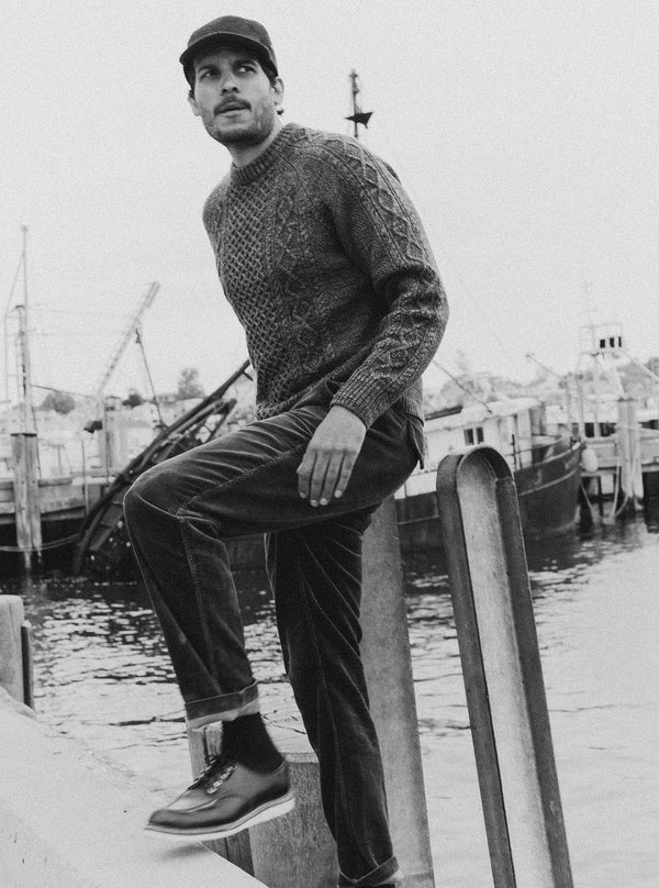 Model walking on a pier in The Orr Sweater in Marled Marine Merino